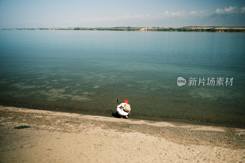 一位快乐的45岁女性背包客正在从盐湖取水并录制视频