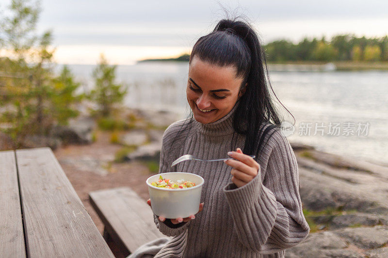 年轻女子在大自然的湖边吃健康的一餐