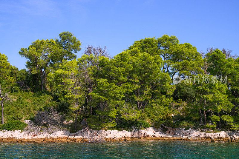 在克罗地亚的亚得里亚海上，蔚蓝的大海，蔚蓝的天空和周围岛屿上的绿色松树，犹如在亚得里亚海上航行的宁静。