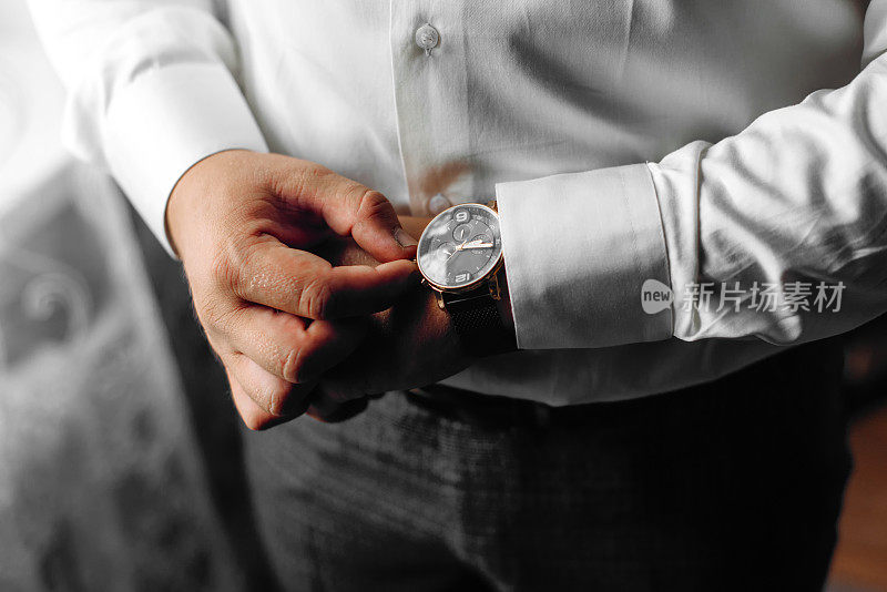 新郎看了看手表看看时间。手表戴在男人的手上。