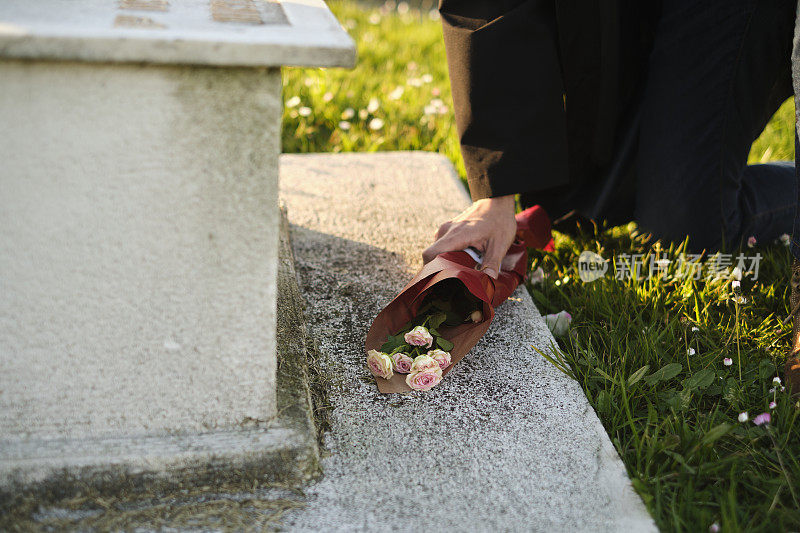 一个男人在墓地的墓碑前献花的特写