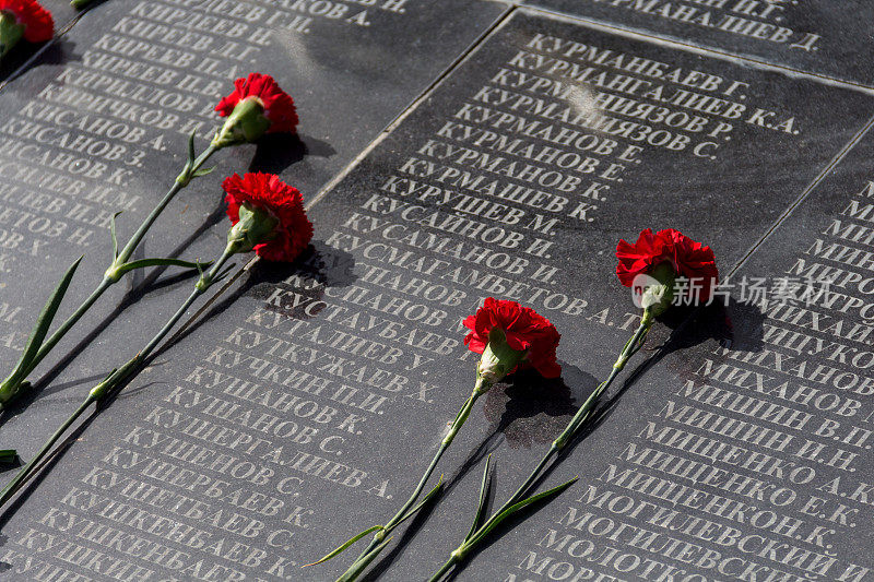 纪念盘上的康乃馨，上面写着遇难者的名字。卫国战争士兵的方尖碑。纪念第二次世界大战死难者的纪念碑
