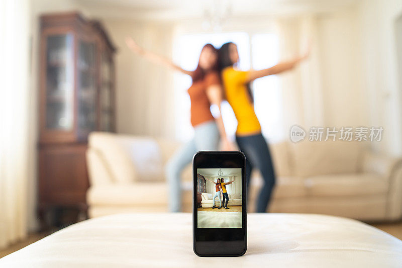 两个年轻女子在照相手机前跳舞