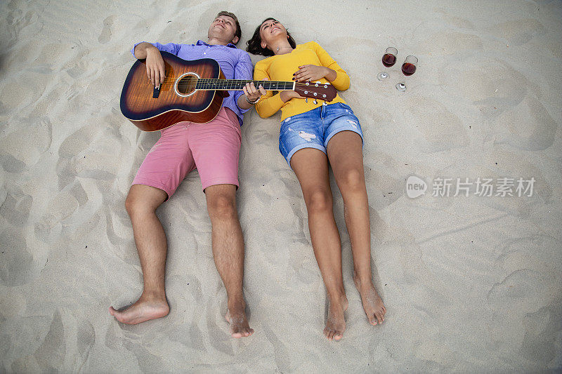 幸福的年轻夫妇躺在沙滩上