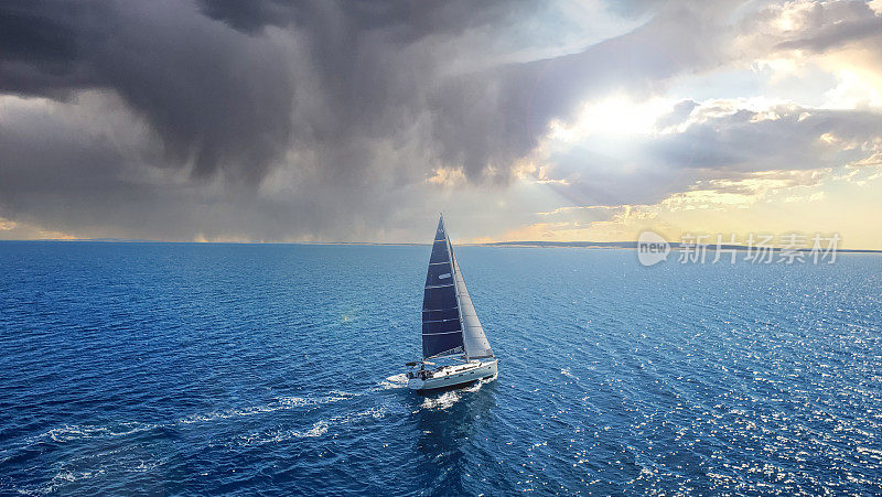 帆船在有风的情况下在海上航行，在日落时远离风暴