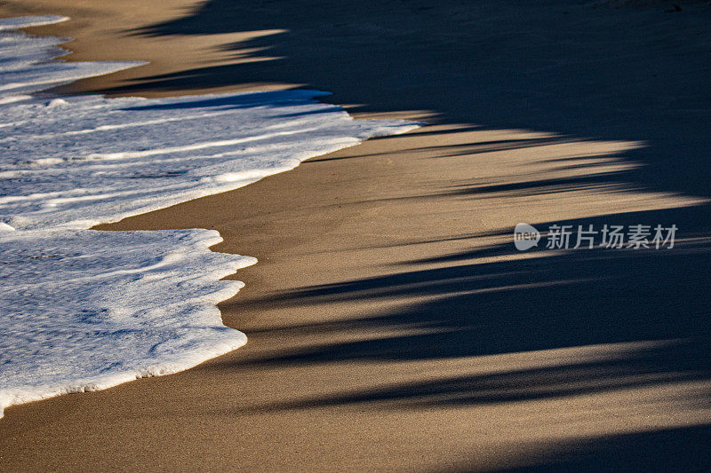 潮水在海岸线上涌动，在海滩上有山的影子