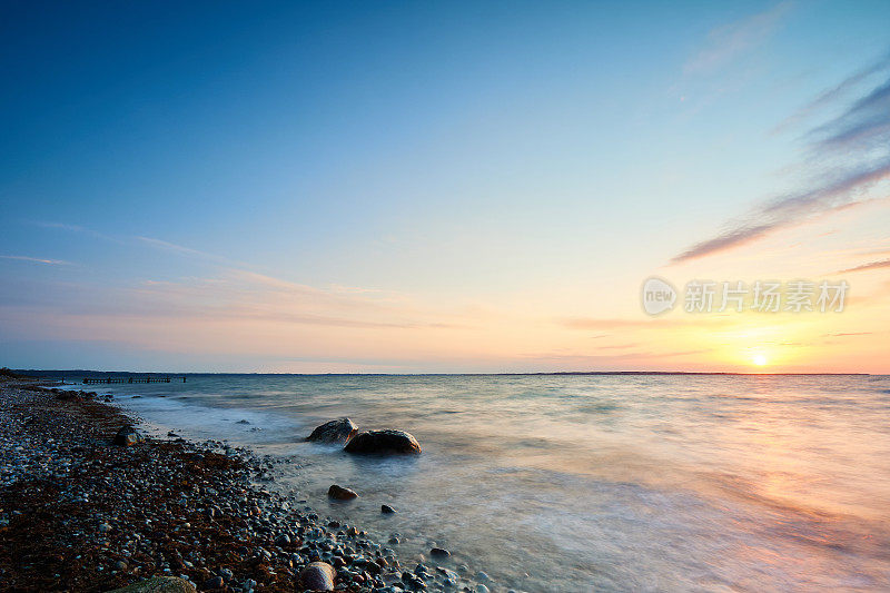 日落时橙色天空映衬下的田园诗般的海景