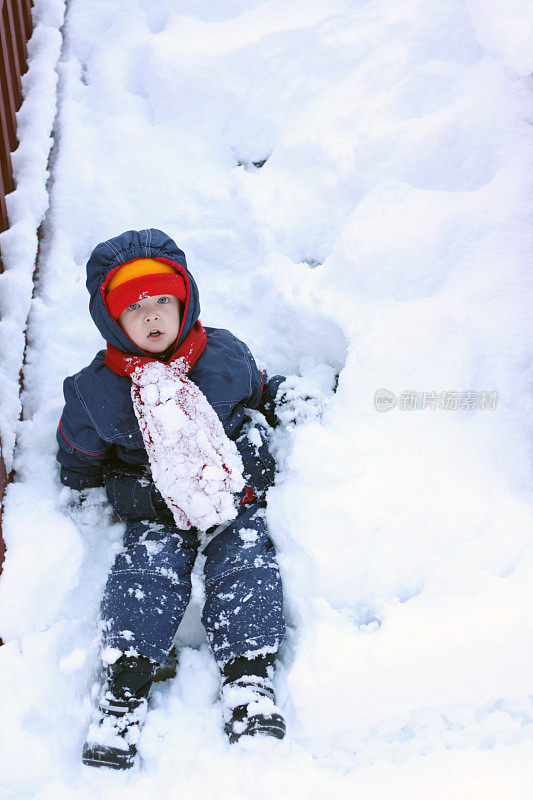 坐在被雪覆盖的甲板楼梯上的男孩