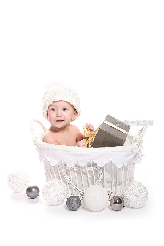 可爱的小女孩坐在圣诞篮子里，竖着拿着礼物