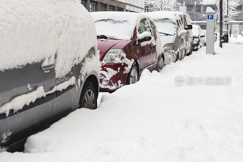 被雪覆盖的汽车停在雪地里的街道上