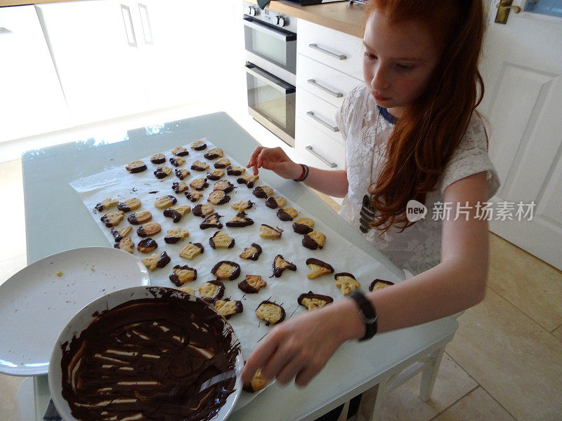 一个小女孩在做万圣节饼干，上面涂着巧克力糖霜
