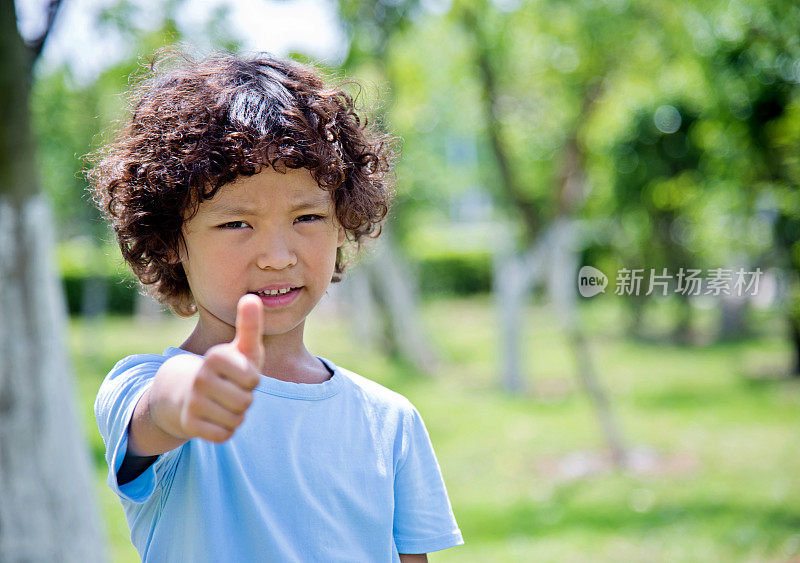 快乐的小男孩在户外竖起大拇指