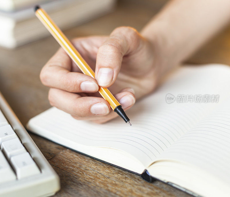 女人的手在笔记本上写日记。
