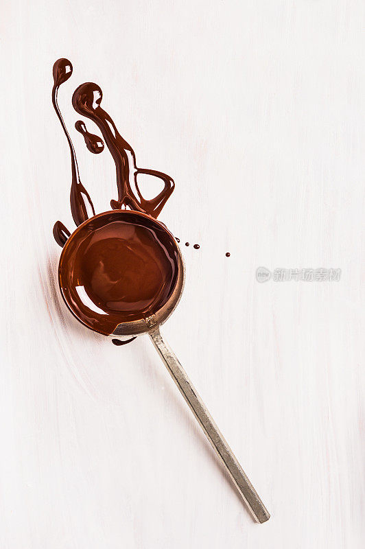 白色木质背景上的液态巧克力勺