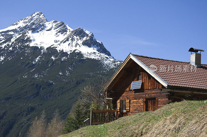 春天里的小木屋，背景是群山