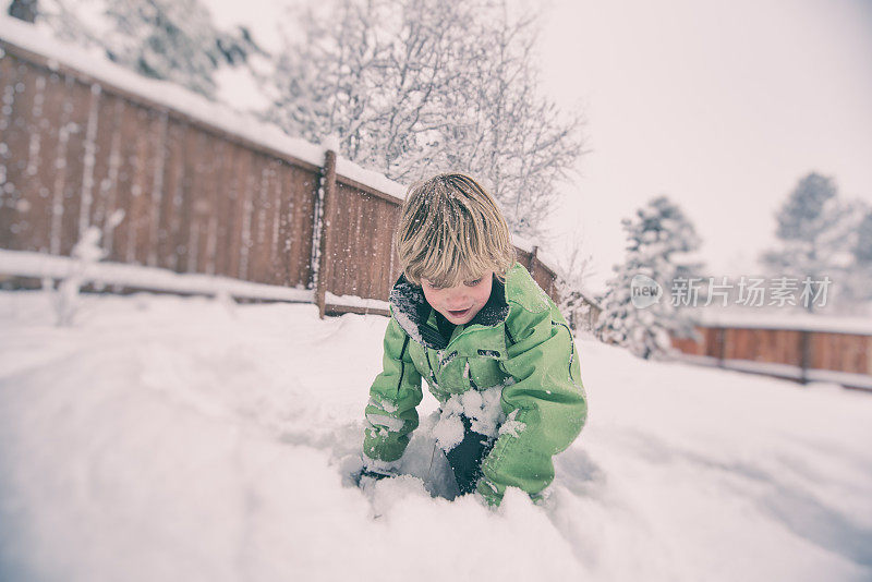 一个男孩在暴风雪中在雪地里爬