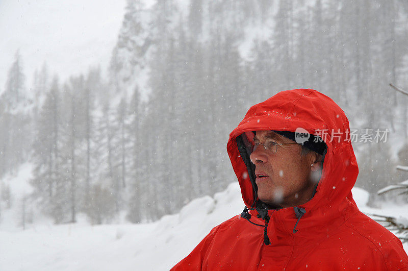 一个穿着红色夹克和帽子的老人在雪地里