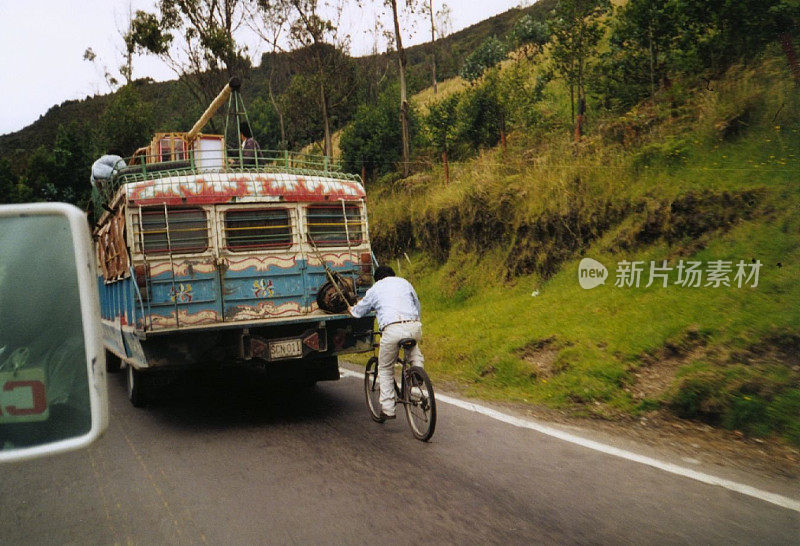 在公路上一辆典型的公共汽车后面徒步旅行的自行车搭便车(哥伦比亚