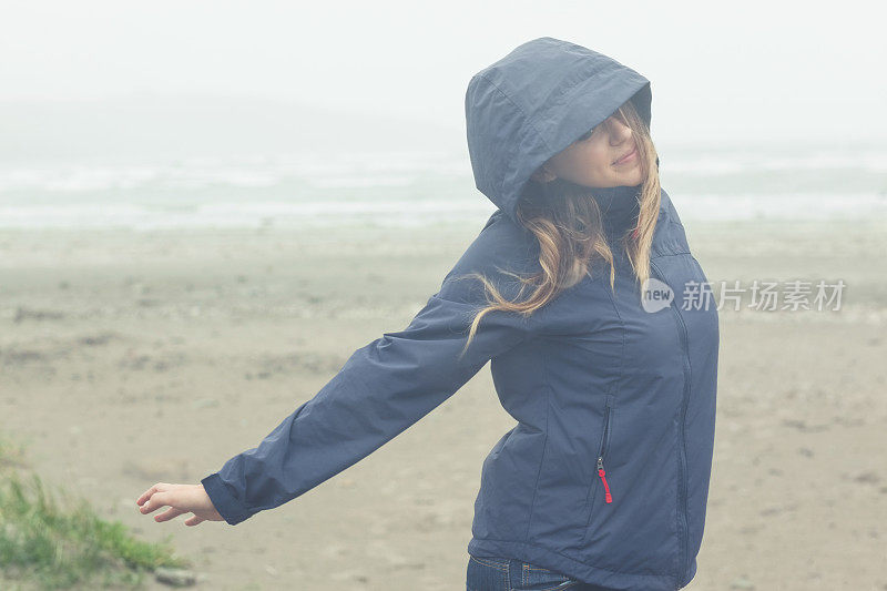 穿着海军蓝雨衣的漂亮模特在海滩上