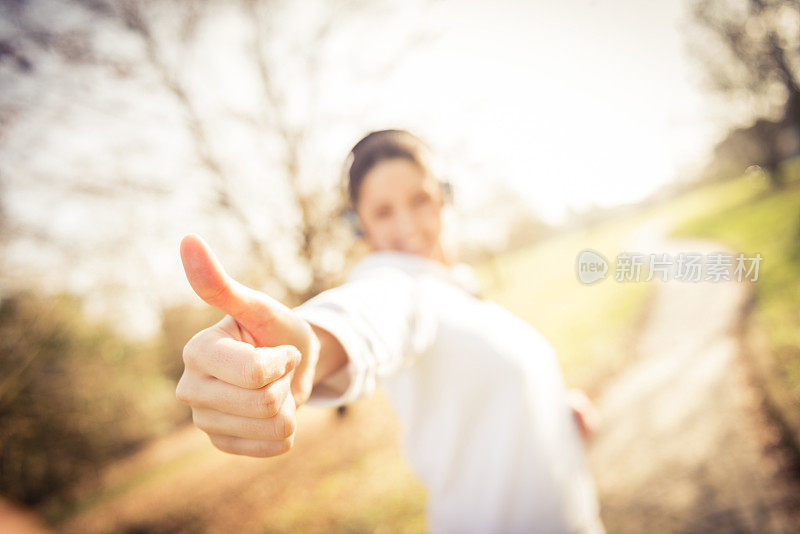 一个年轻快乐的女人举着一个竖起大拇指的牌子