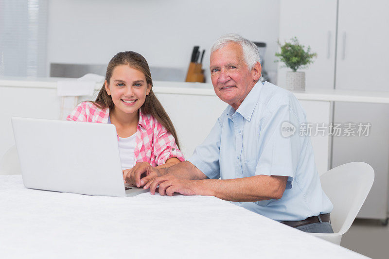 带着笔记本电脑微笑的爷爷和孙女