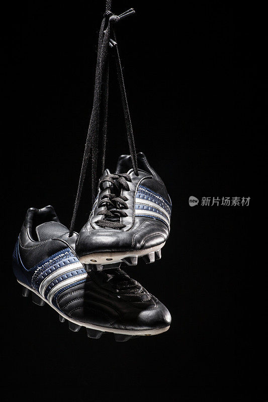 足球鞋挂在黑色的背景上