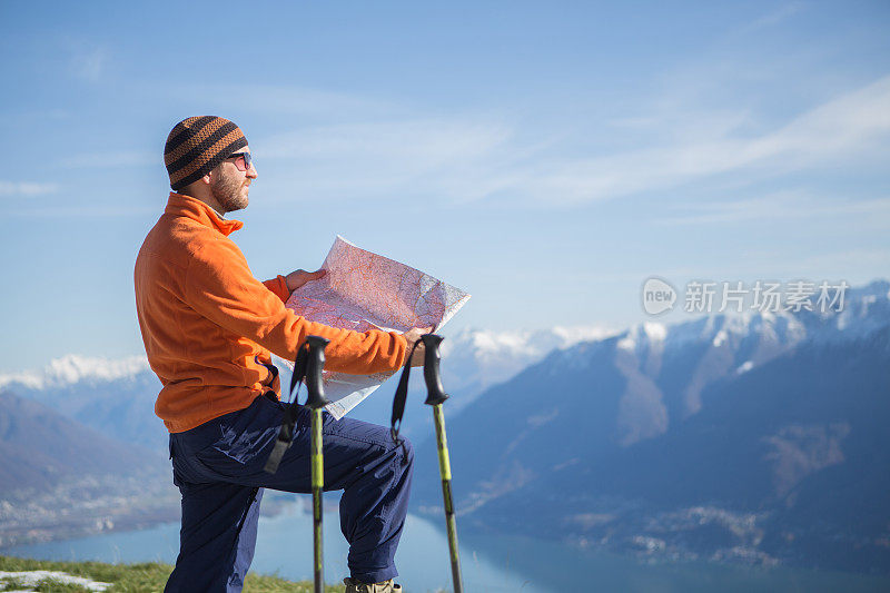 游客在高山上徒步旅行，阅读地图寻找方向