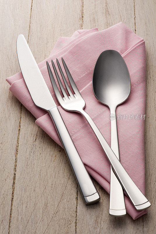 叉子，刀子和勺子放在粉色的餐巾上