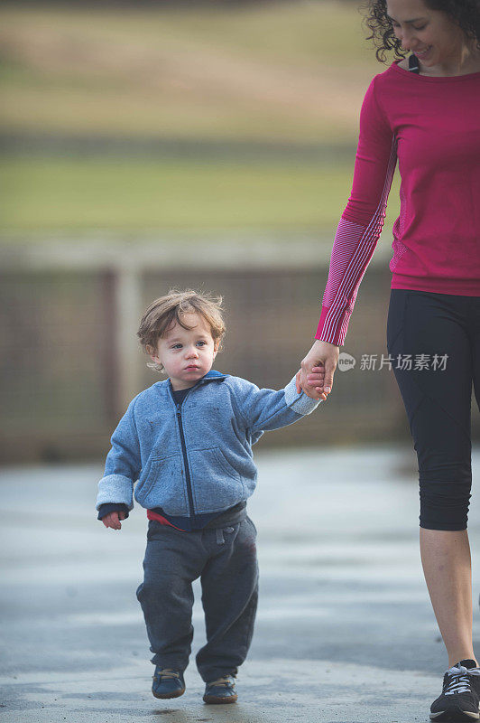 年轻活泼的欧亚妈妈带着两岁的儿子在外面散步