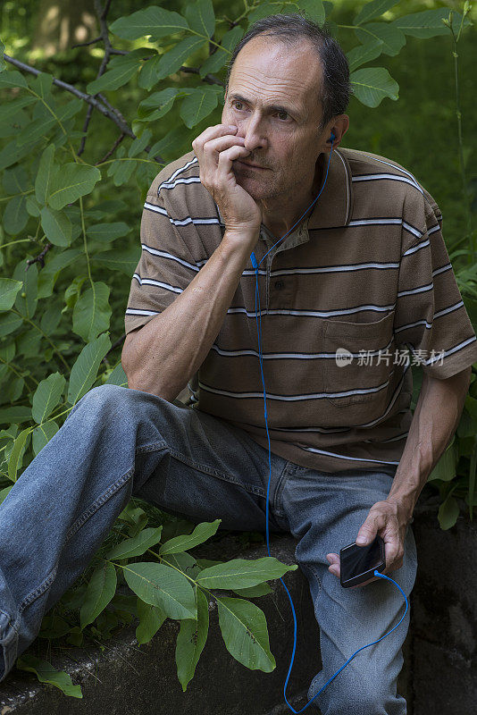 成熟的男人在花园里听着节目