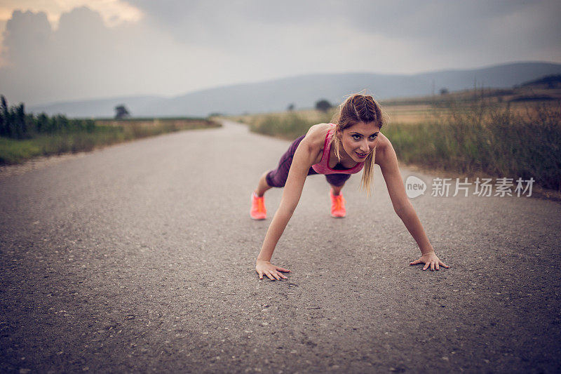 运动女孩在乡村公路上做俯卧撑