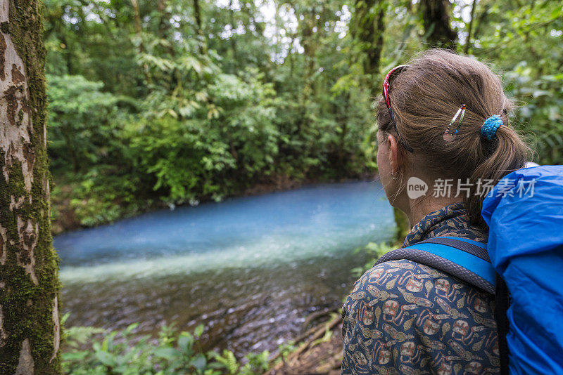 在哥斯达黎加的特诺里奥火山国家公园，一位年长的妇女正在看着河流的颜色