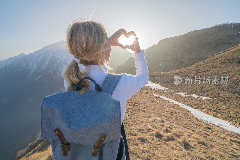 年轻女子在山路上做心形框架