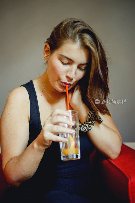 快乐的年轻女子在咖啡厅喝果汁
