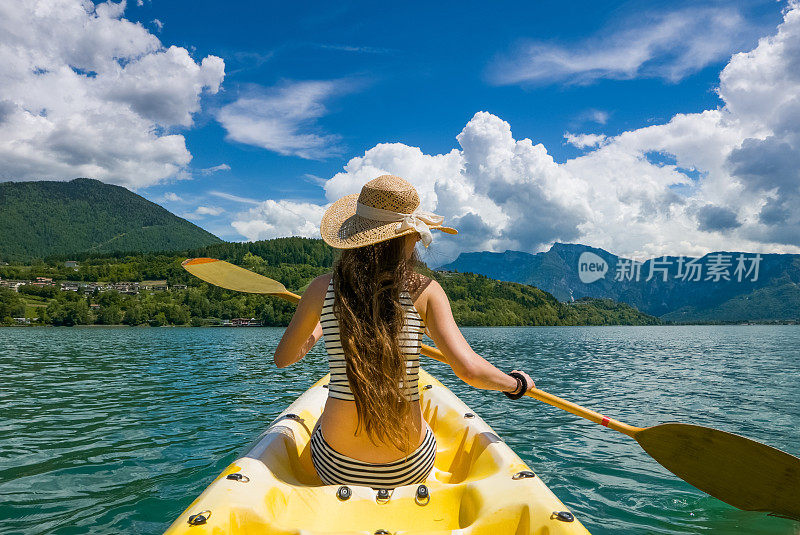 长头发的年轻女子在阳光下划皮艇