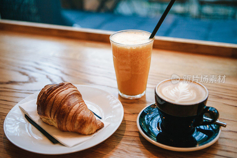 法式传统羊角面包甜点，在咖啡馆里的咖啡卡布奇诺和橙汁旁边作为早餐。