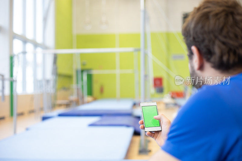 体操运动员在训练间歇使用绿屏手机