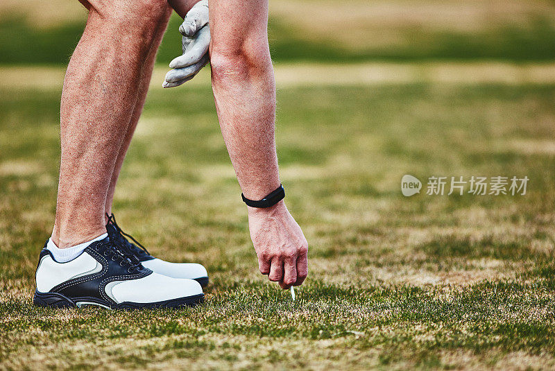 男性高尔夫球手佩戴健身追踪器将高尔夫球放在球座上