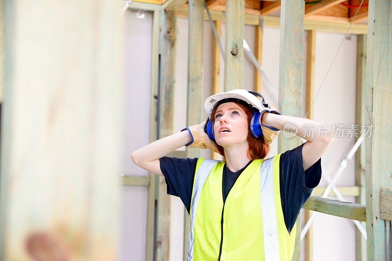女建筑工人用手捂着耳朵干活