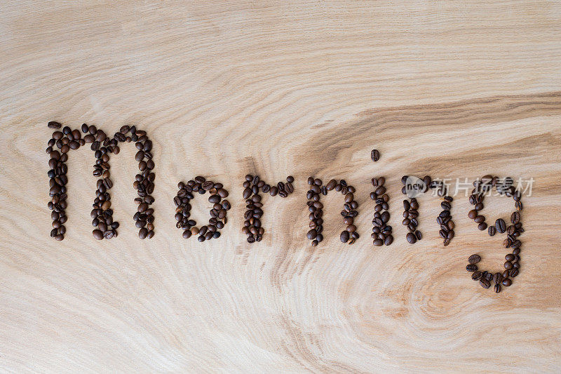 “早晨”这个词是用咖啡粒铺在木头背景上的