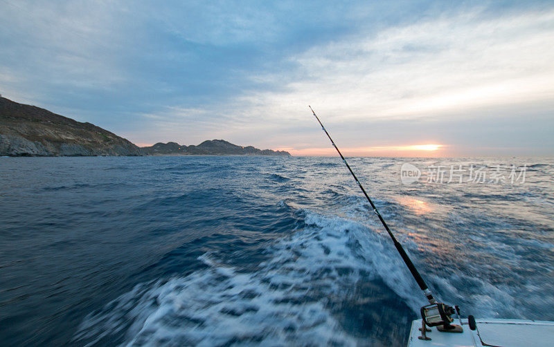 在墨西哥下加利福尼亚卡波圣卢卡斯太平洋边的租渔船上的钓鱼竿的日出视图