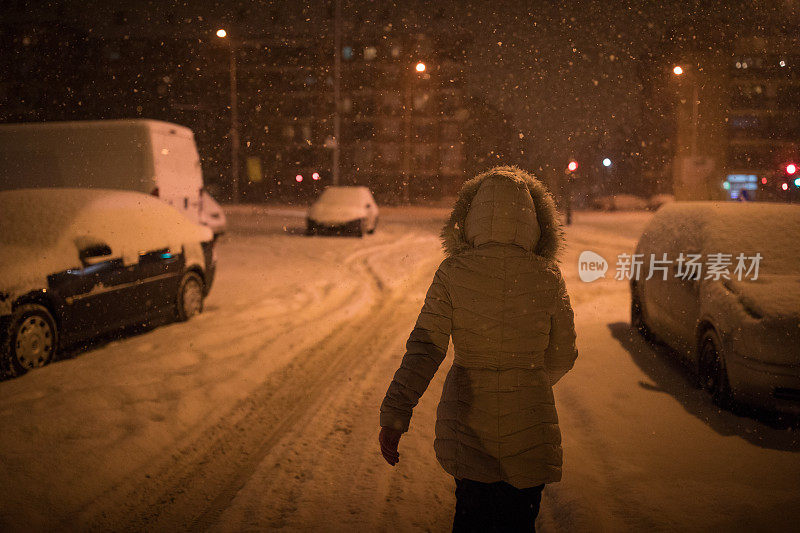 一个女人在下雪的晚上散步