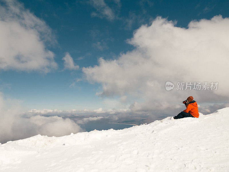 女性高山攀登者在冬季日出时在高海拔的山峰上喝咖啡