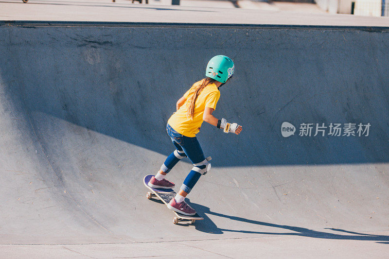 年轻女孩滑板在四分之一管在滑板公园