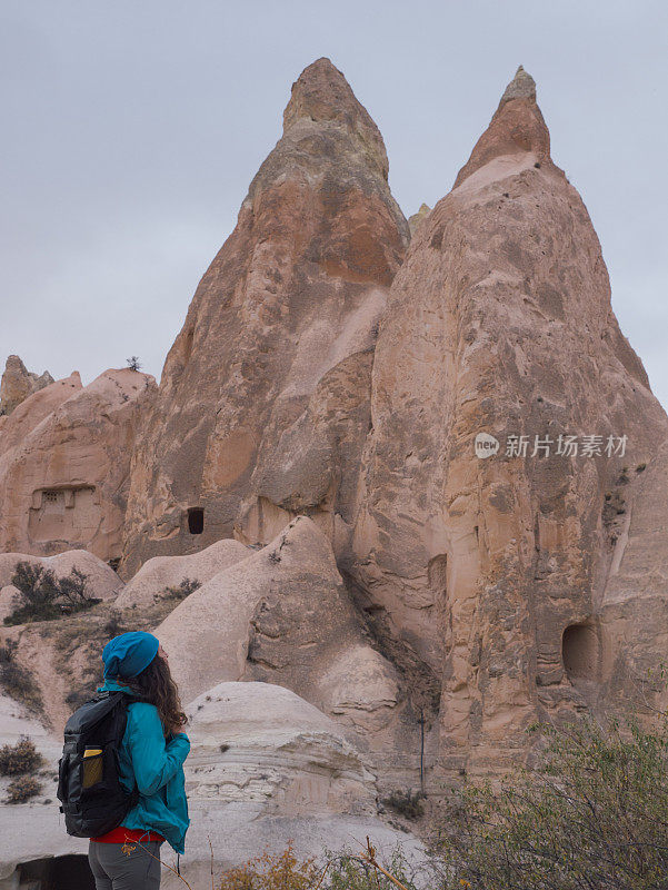 在土耳其卡帕多西亚的戈雷米红玫瑰山谷里，一个年轻的女孩正在观看一间窑洞