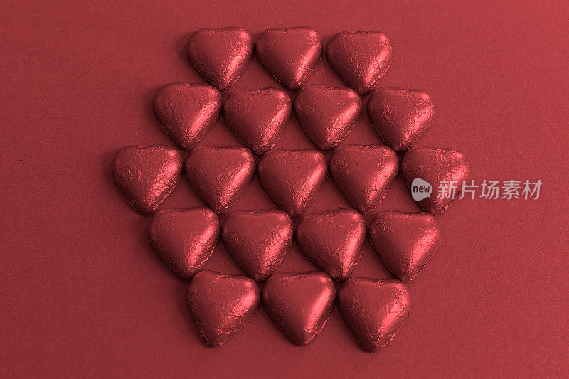 心形巧克力放置在一个六角形的图案上，背景是勃艮第
