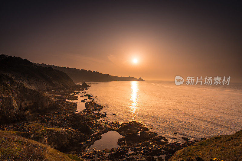 日出在一个夏天沿着悬崖小径散步，崎岖的海岸线和平静的水