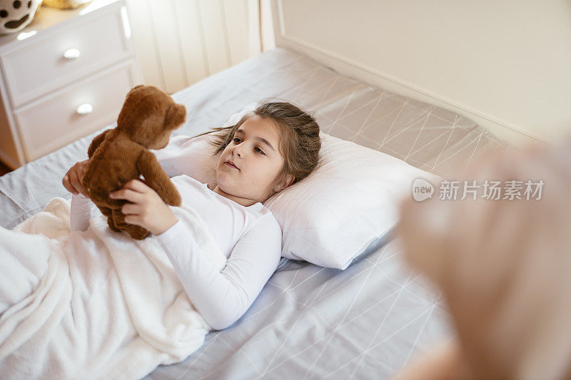 漂亮女孩和她的泰迪熊在床上