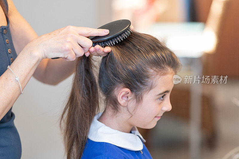 意大利教育理念。回到学校。妈妈在去上学前给女儿梳头。女儿穿制服