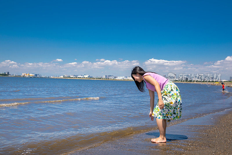 一名年轻女子在海滩上触碰海水